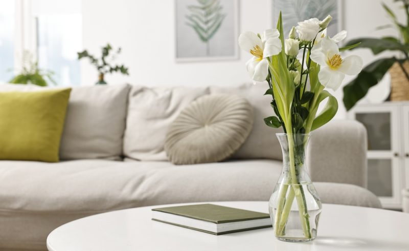 Feng shui. Vase avec fleurs et livre sur table blanche à l'intérieur.