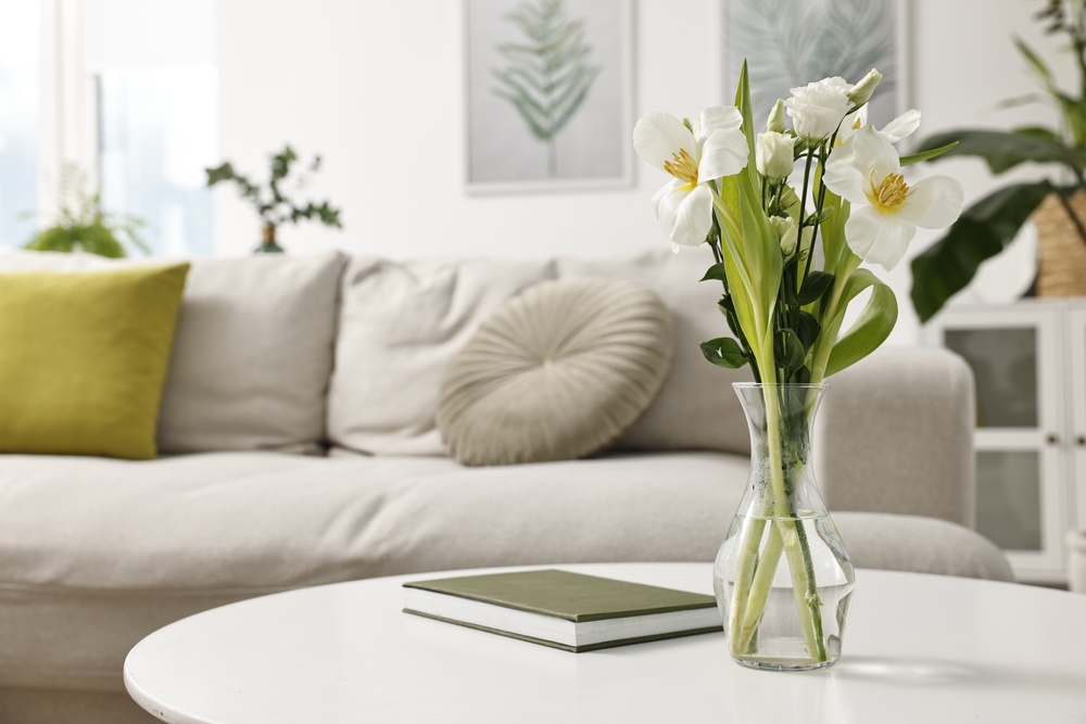 Feng shui. Vase avec fleurs et livre sur table blanche à l'intérieur.